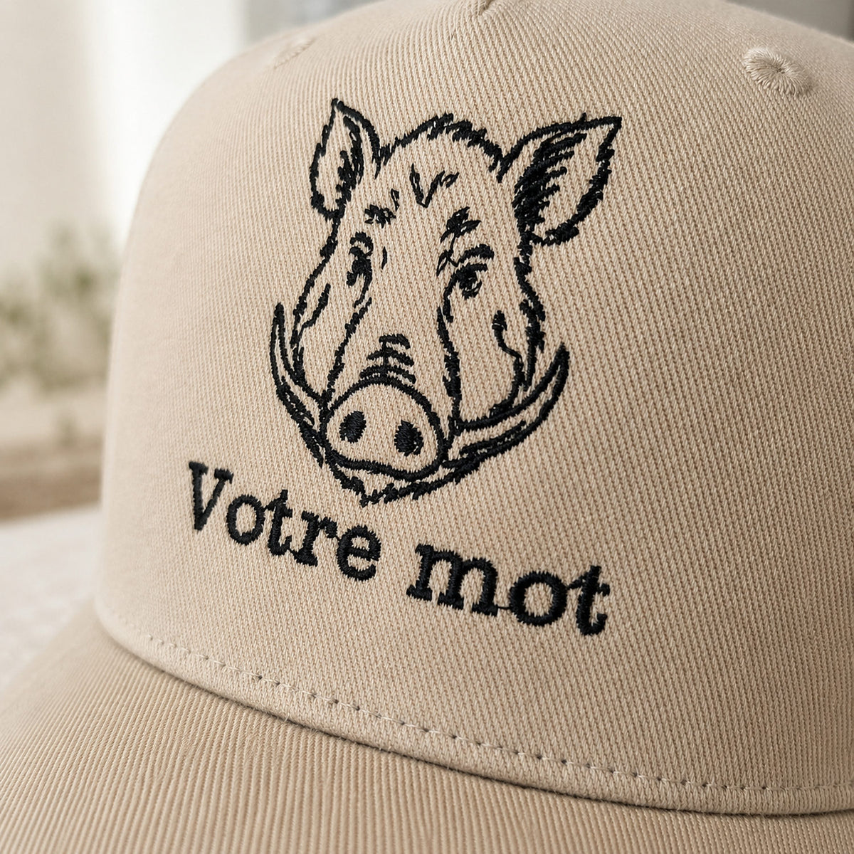 Détail de la broderie tête de sanglier fil noir sur casquette de chasse beige