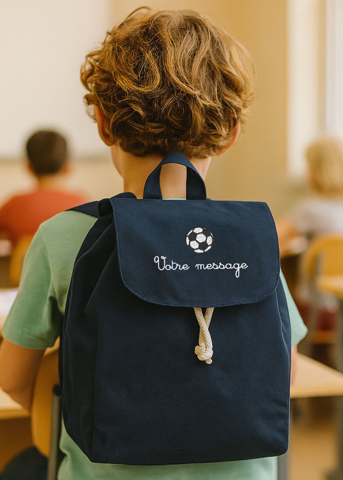 Sac à dos bleu marine personnalisé avec prénom brodé, porté par un enfant en classe.