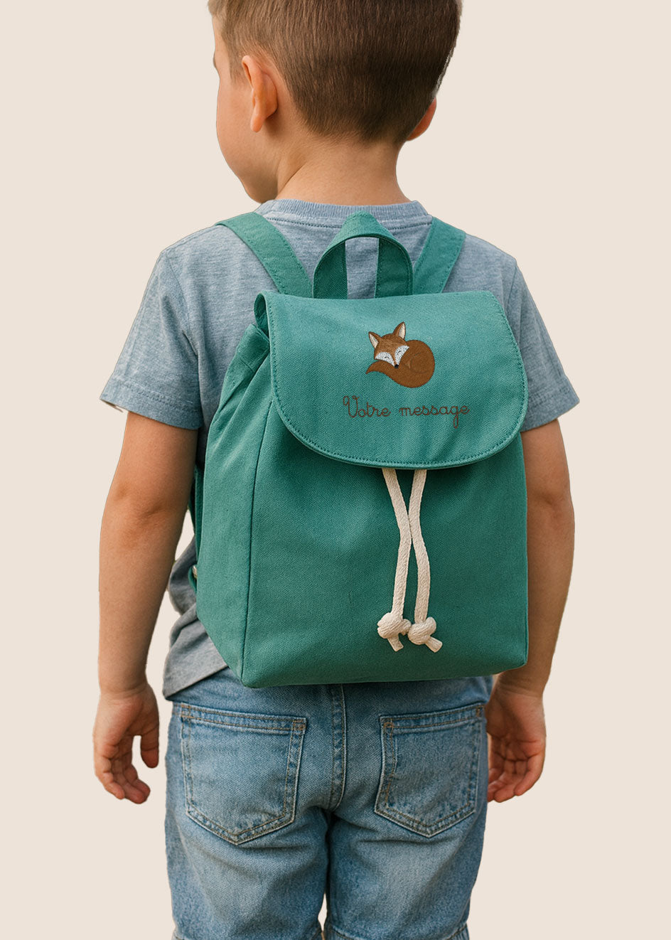Sac à dos vert pour enfant, porté par un petit garçon de dos, personnalisable avec prénom brodé.