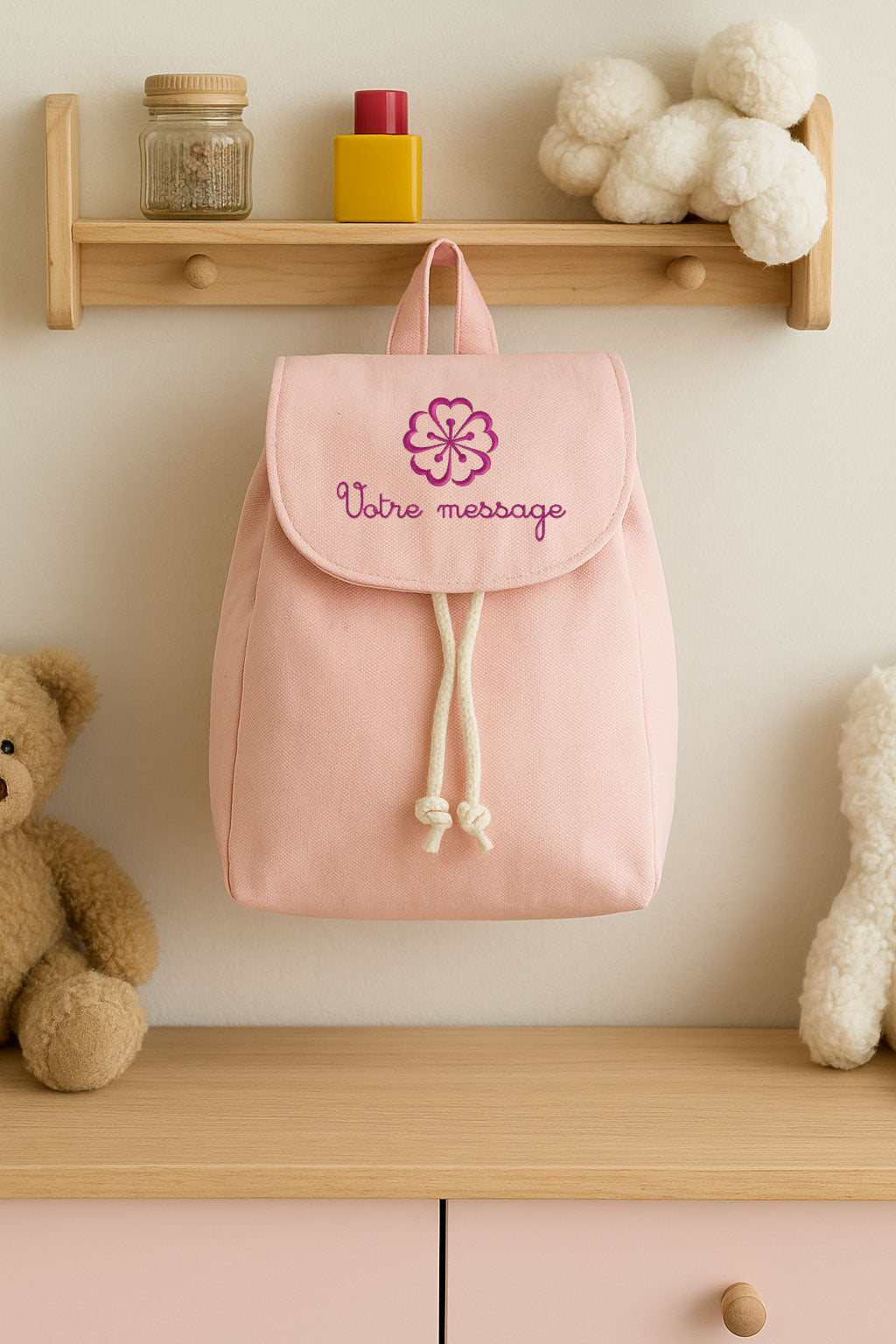 Sac à dos rose pour enfant accroché dans une chambre, personnalisable avec prénom brodé.