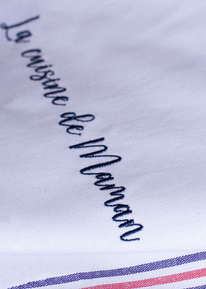 Gros plan d'une broderie personnalisée sur un torchon de cuisine en coton, confection française, avec l'inscription « La cuisine de Maman ».