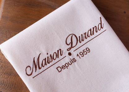 Photo reelle de la broderie personnalisee sur un torchon de cuisine Maison personnalise fabrique en France.