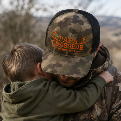Père portant une casquette camouflage brodée Papa Chasseur avec son enfant dans les bras