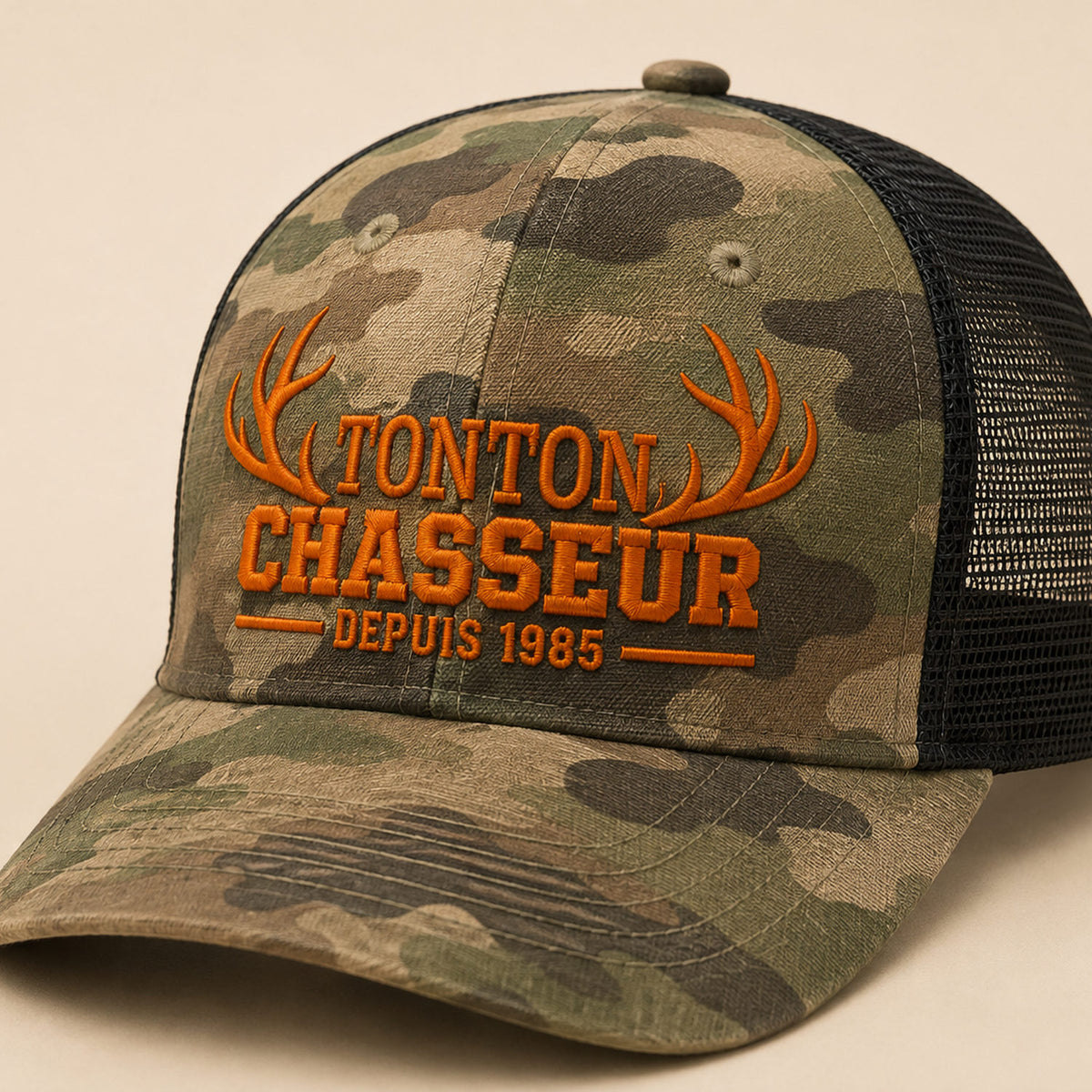 Détail de la broderie orange Tonton Chasseur et bois de cerf sur casquette camouflage