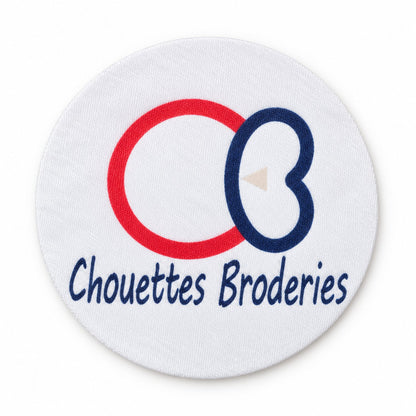 Écusson sublimé personnalisé rond sur fond tissu blanc, logo imprimé en rouge et bleu marine avec tracés nets et couleurs illimitées