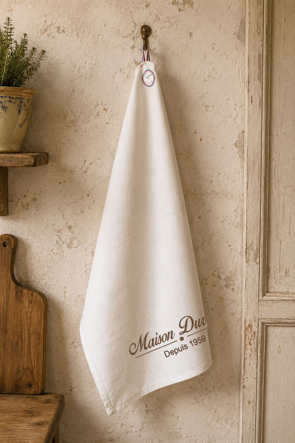Torchon personnalisé Made in France avec broderie Maison Durand suspendu dans une cuisine vintage. Cadeau personnalisé pour la cuisine, brodé en France.