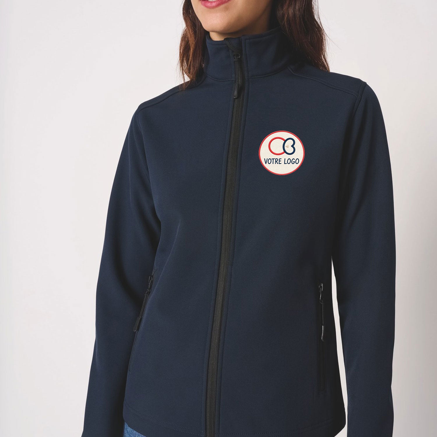 Femme portant une veste softshell bleu marine avec broderie logo côté cœur, iDeal Basic IB411